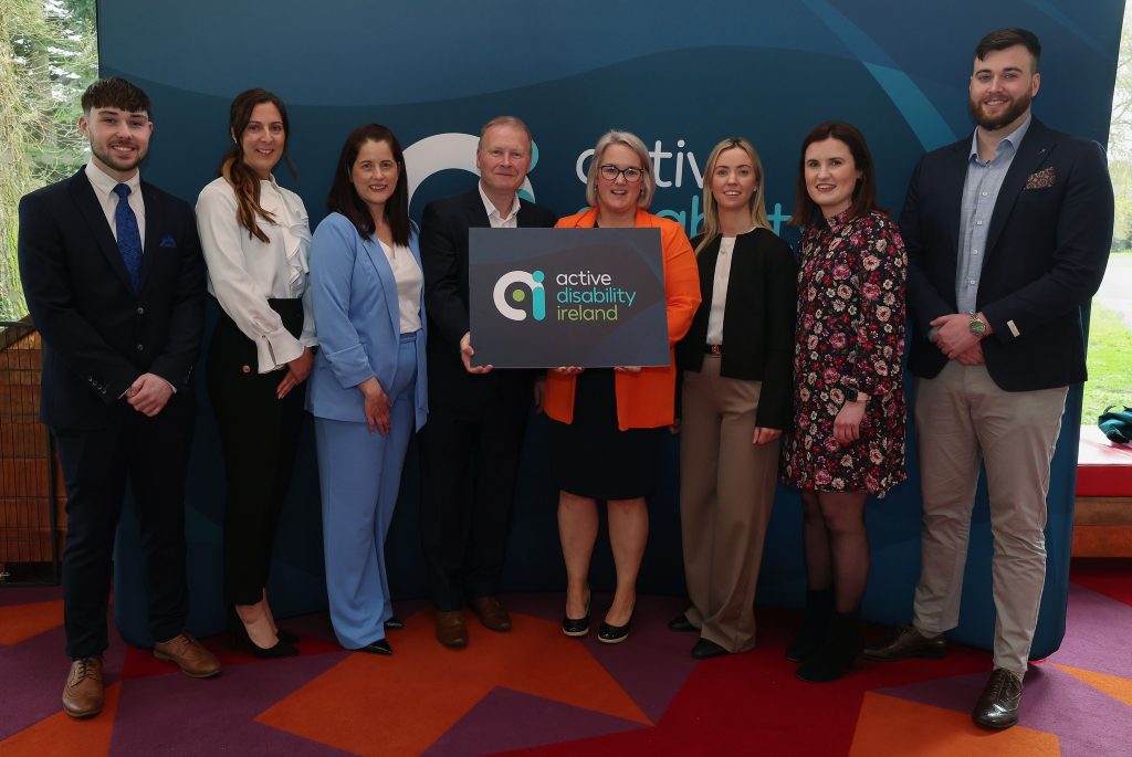 The Active Disability Ireland team at the recent re-brand launch event holding a cut-out image of the new name and brand identity.